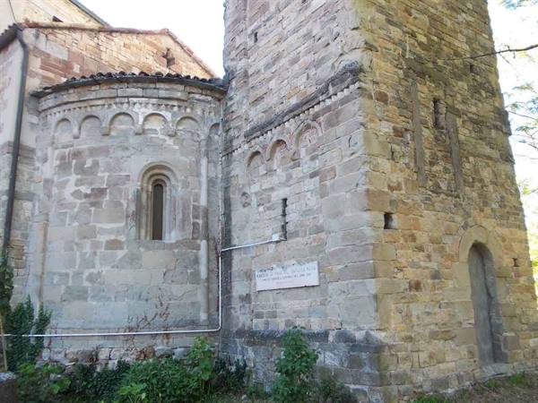 Romanesque stone apse and bell tower with paired windows at Rivalta