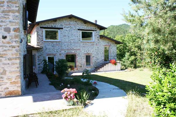 Stone farmhouse with flowered garden and path among greenery