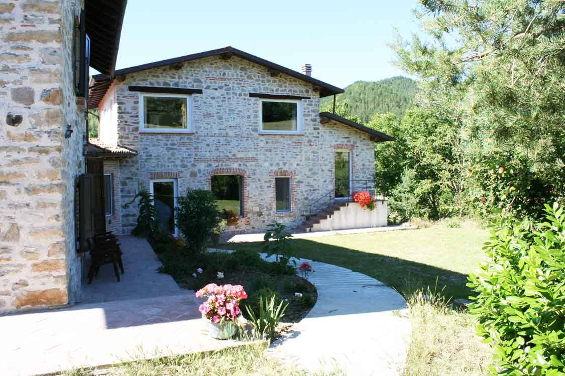 Casa rurale in pietra con giardino fiorito e vialetto tra il verde