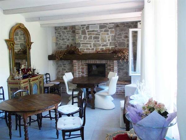 Dining room with stone fireplace, round wooden tables and antique gilded mirror