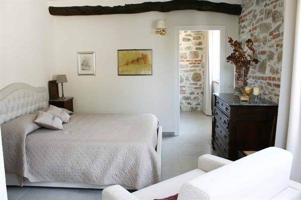 Bedroom with double bed, wooden beam and stone wall
