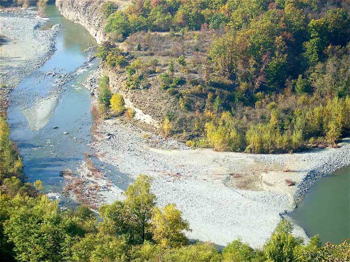 Fiume con ghiaioni tra boschi autunnali, curve d'acqua tra rive sassose