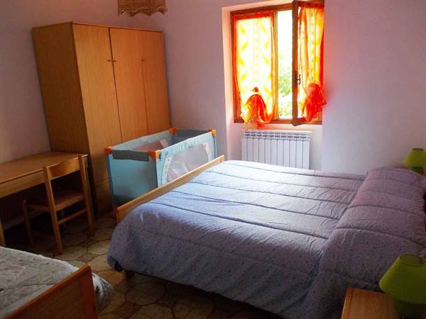 Bedroom with double bed, wooden wardrobe and travel crib by the window