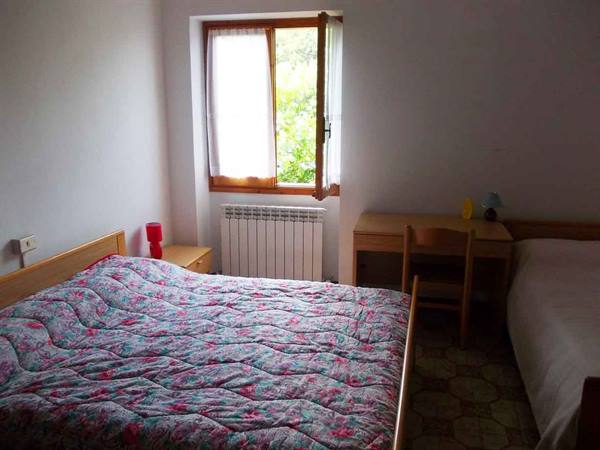 Bedroom with bunk bed covered in floral quilt, window open onto greenery