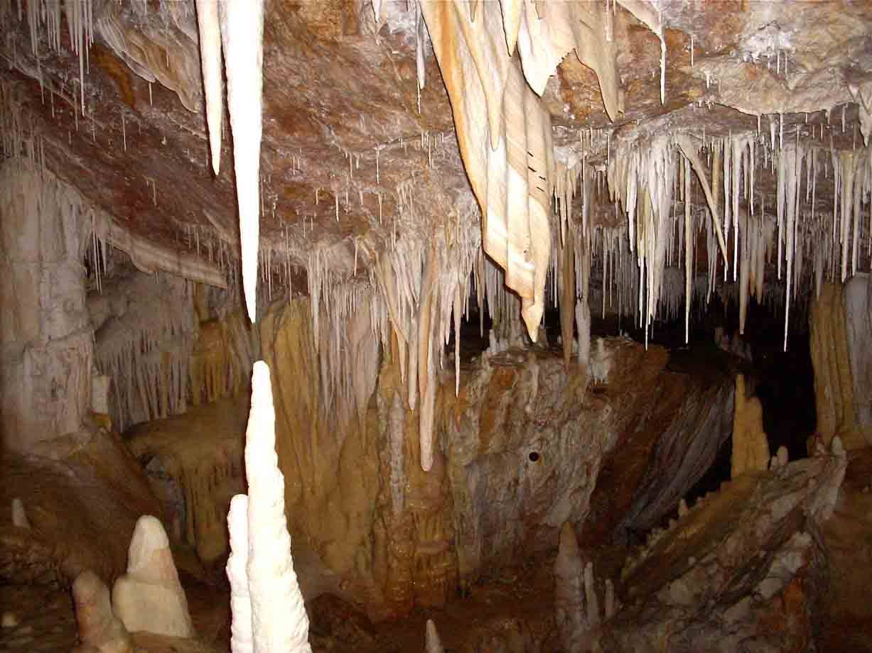 Grotta con stalattiti e stalagmiti di calcare illuminata da luce artificiale