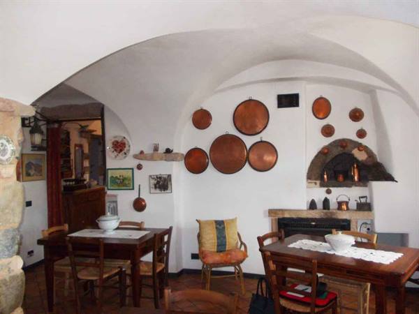 White vaulted dining room with copper pans hanging, wooden tables