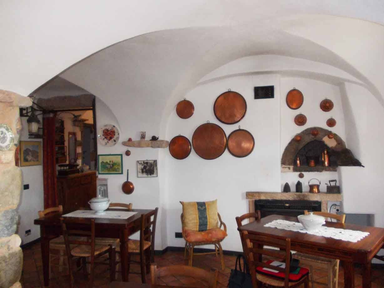 Sala interna con volte bianche e padelle di rame appese, tavoli in legno