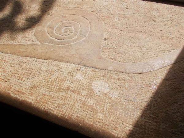 Spiral carving etched into sandstone, lit by sunlight
