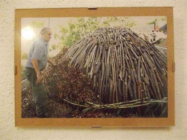 Man beside a dome of wooden sticks, framed photo on the wall