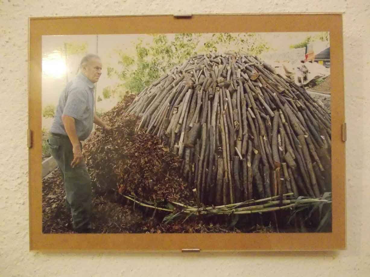Uomo accanto a una cupola di rami di legno, foto incorniciata al muro