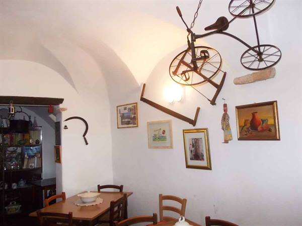 White vaulted room with old bicycle hanging from ceiling, wooden table