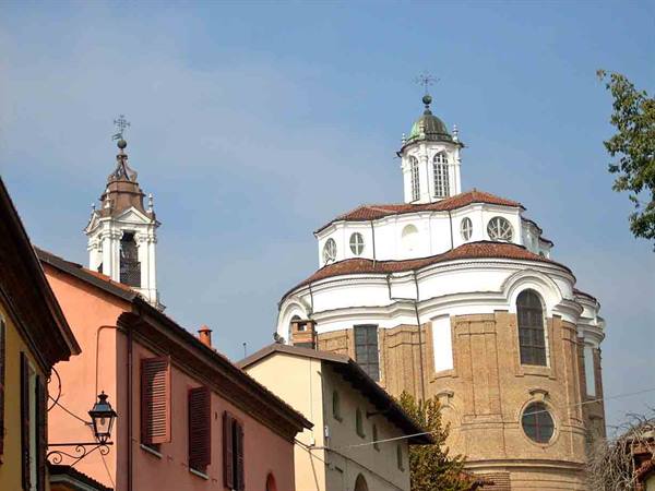 Baroque brick church with octagonal dome above colorful houses, morning light