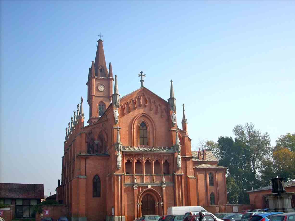 Chiesa neogotica in mattoni rossi con campanile e guglie sotto cielo azzurro