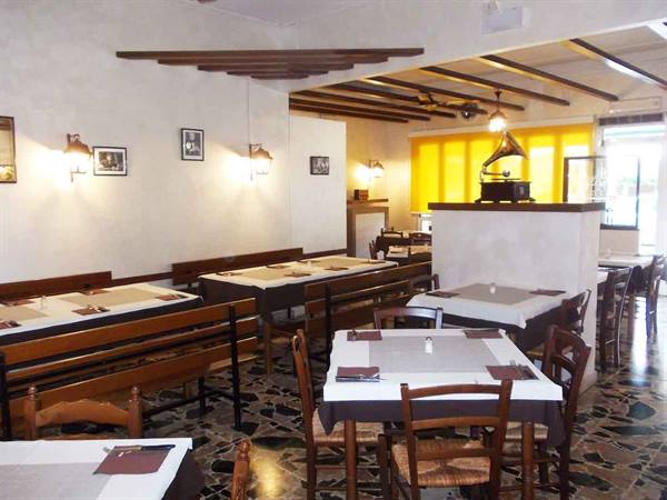 Trattoria dining room with set tables, wooden benches and antique gramophone