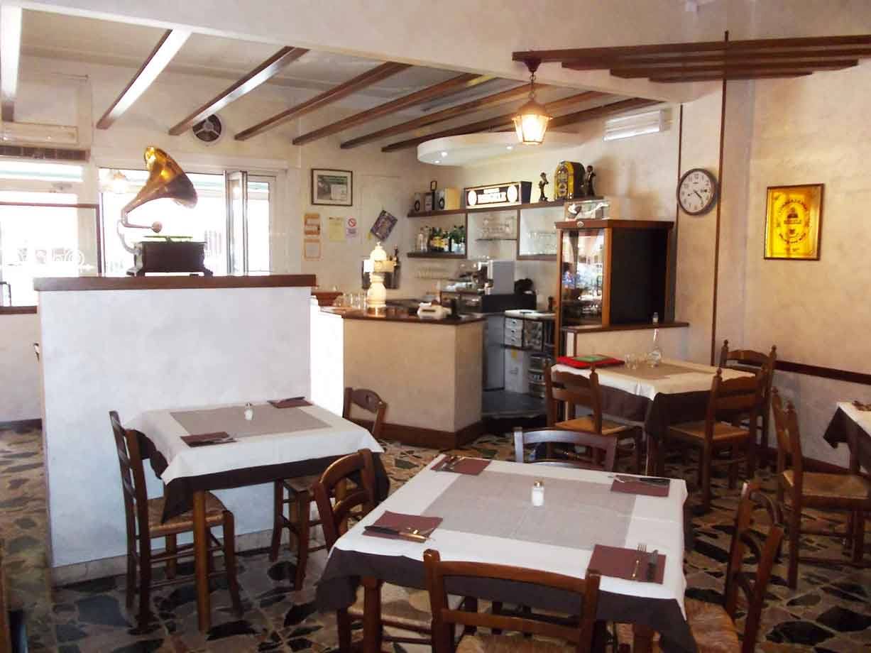 Sala da pranzo con tavoli apparecchiati, gramofono d'epoca e bancone con macchina da caffè