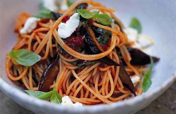 Spaghetti with tomato, eggplant, basil and ricotta in white bowl