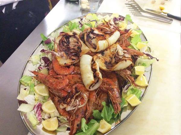Metal platter with grilled prawns, calamari, salad and lemon wedges