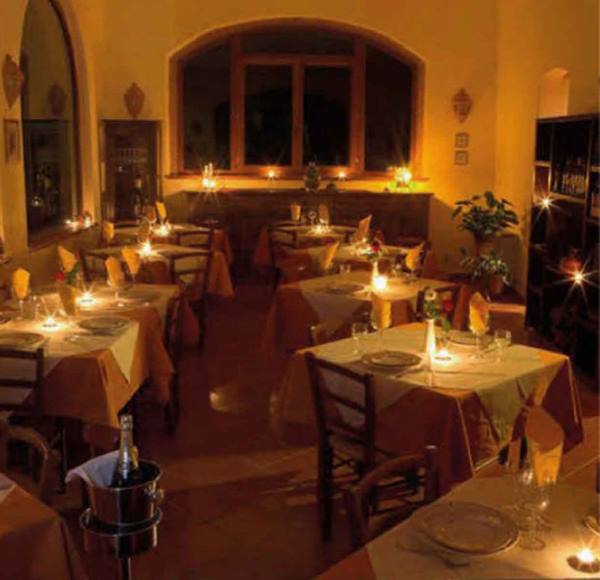 Restaurant dining room with set tables, orange tablecloths and lit candles