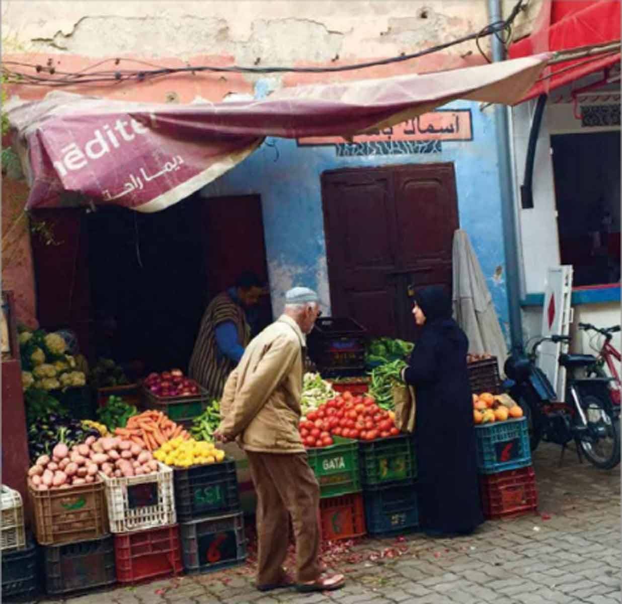 Anziano comprave verdure al banco di un mercatino di strada a Marrakech