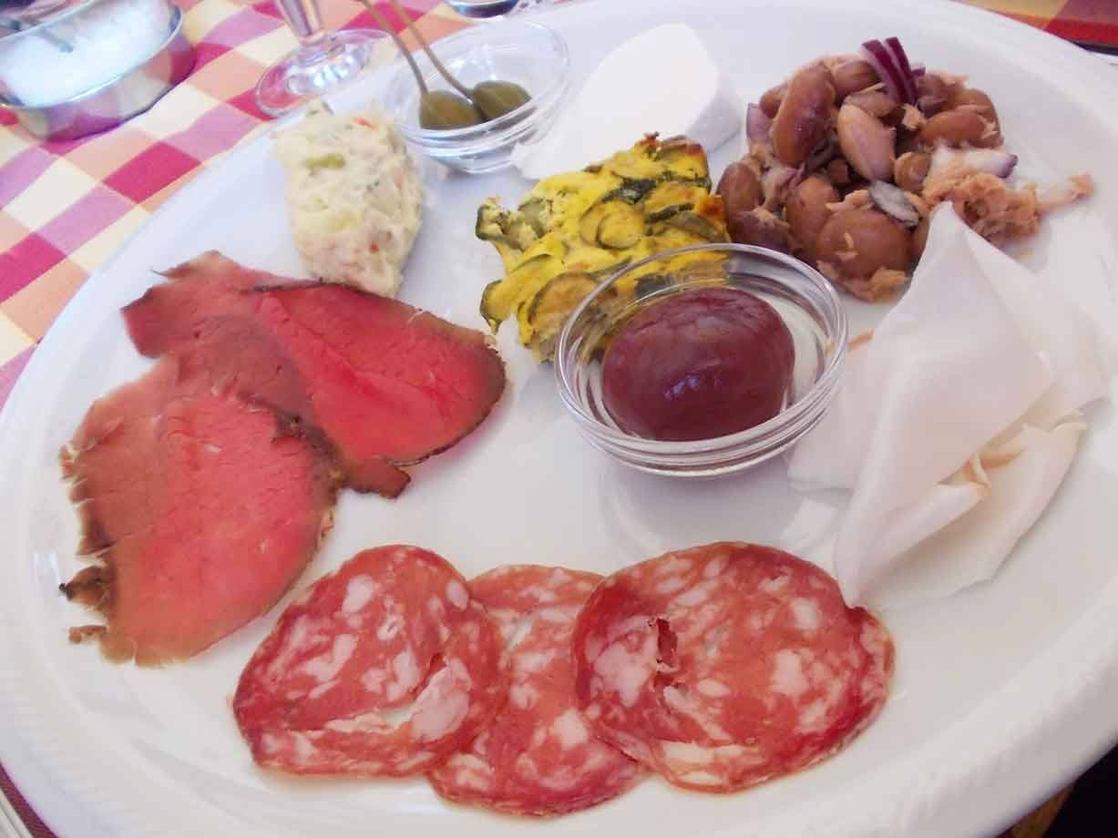 Piatto di antipasti con roastbeef, salame, lardo, fagioli e olive