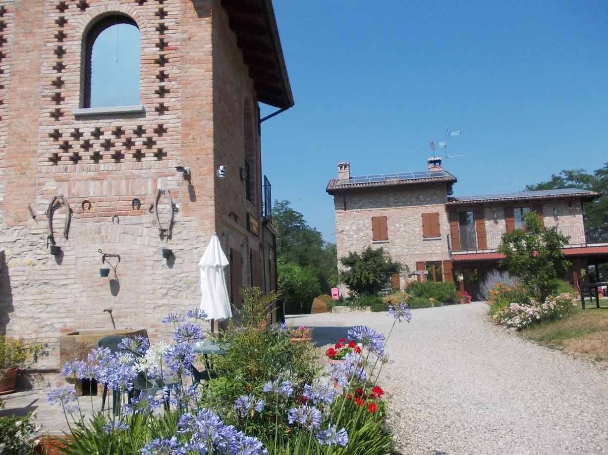 Casale in mattoni con fiori viola e vialetto di ghiaia