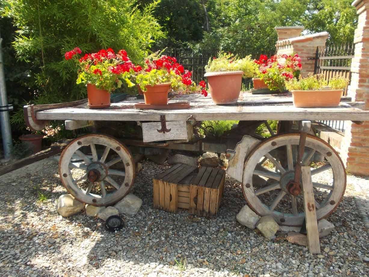 Carretto di legno con ruote di legno, adorno di vasi di gerani rossi al sole