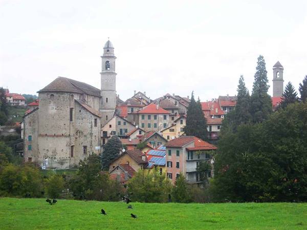 Village of red-roofed houses and stone bell towers among trees