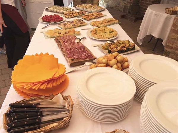 Buffet table with cured meats, savory pies and stacked plates in a courtyard
