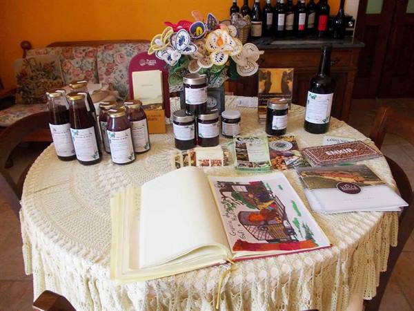 Round table with crochet tablecloth, jam jars, wine bottles and an open guestbook