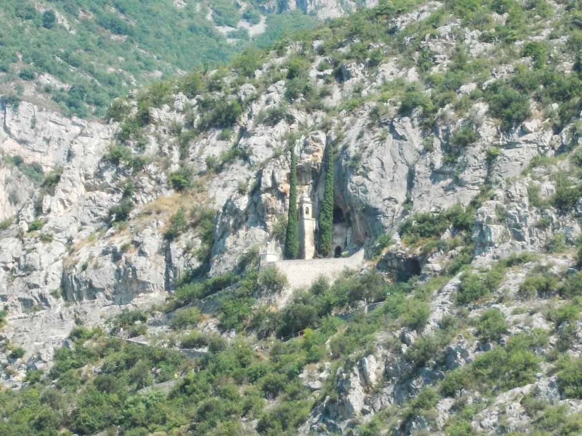 Eremo di Santo Spirito a Majella, cappella con campanile incastonata nella roccia tra cipressi