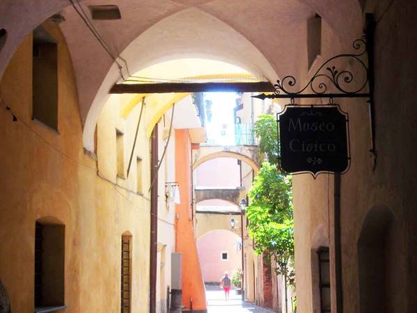 Wrought iron Museo Civico sign beneath the arches of a painted alley