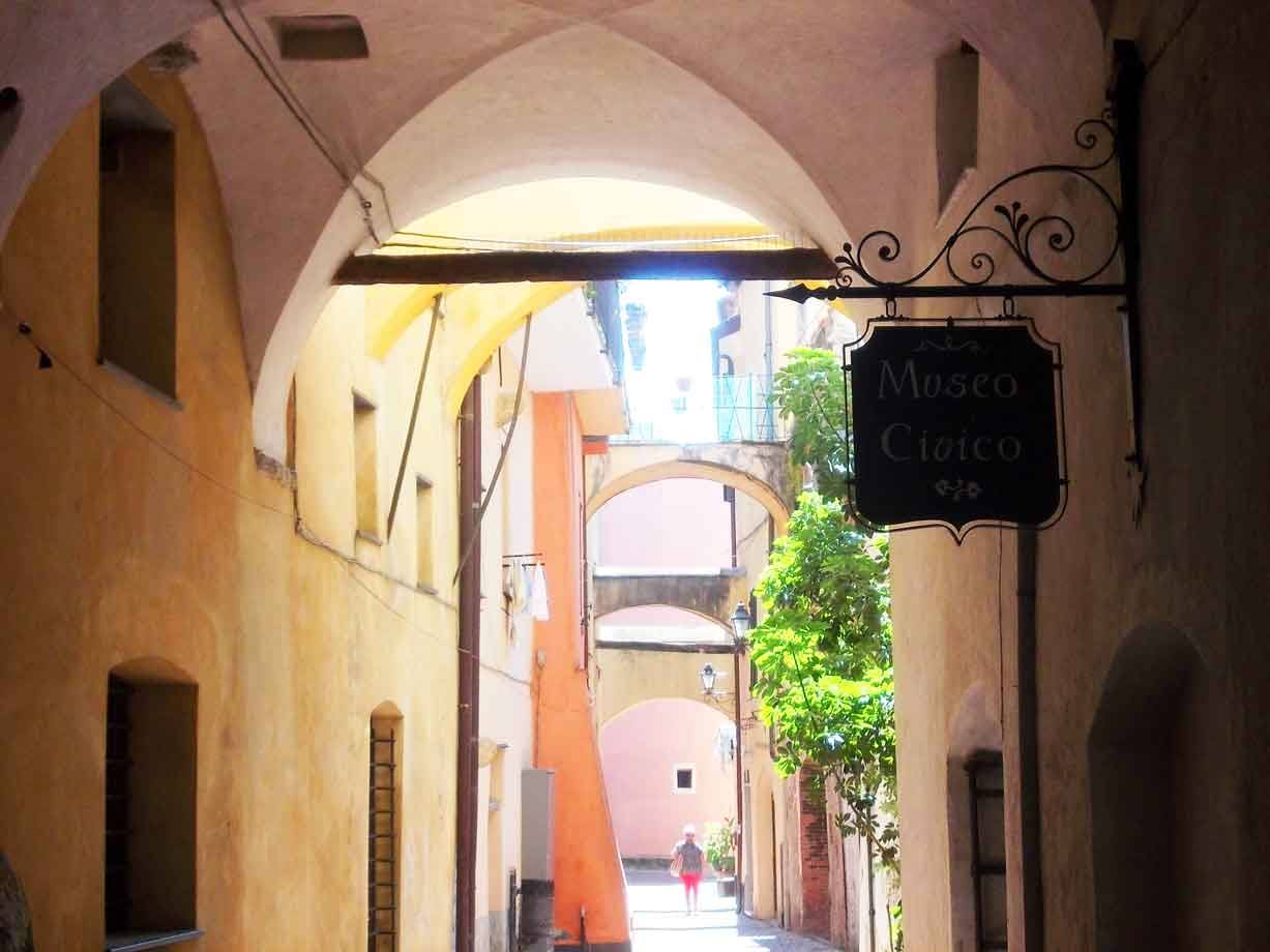 Insegna in ferro del Museo Civico sotto gli archi di un vicolo affrescato