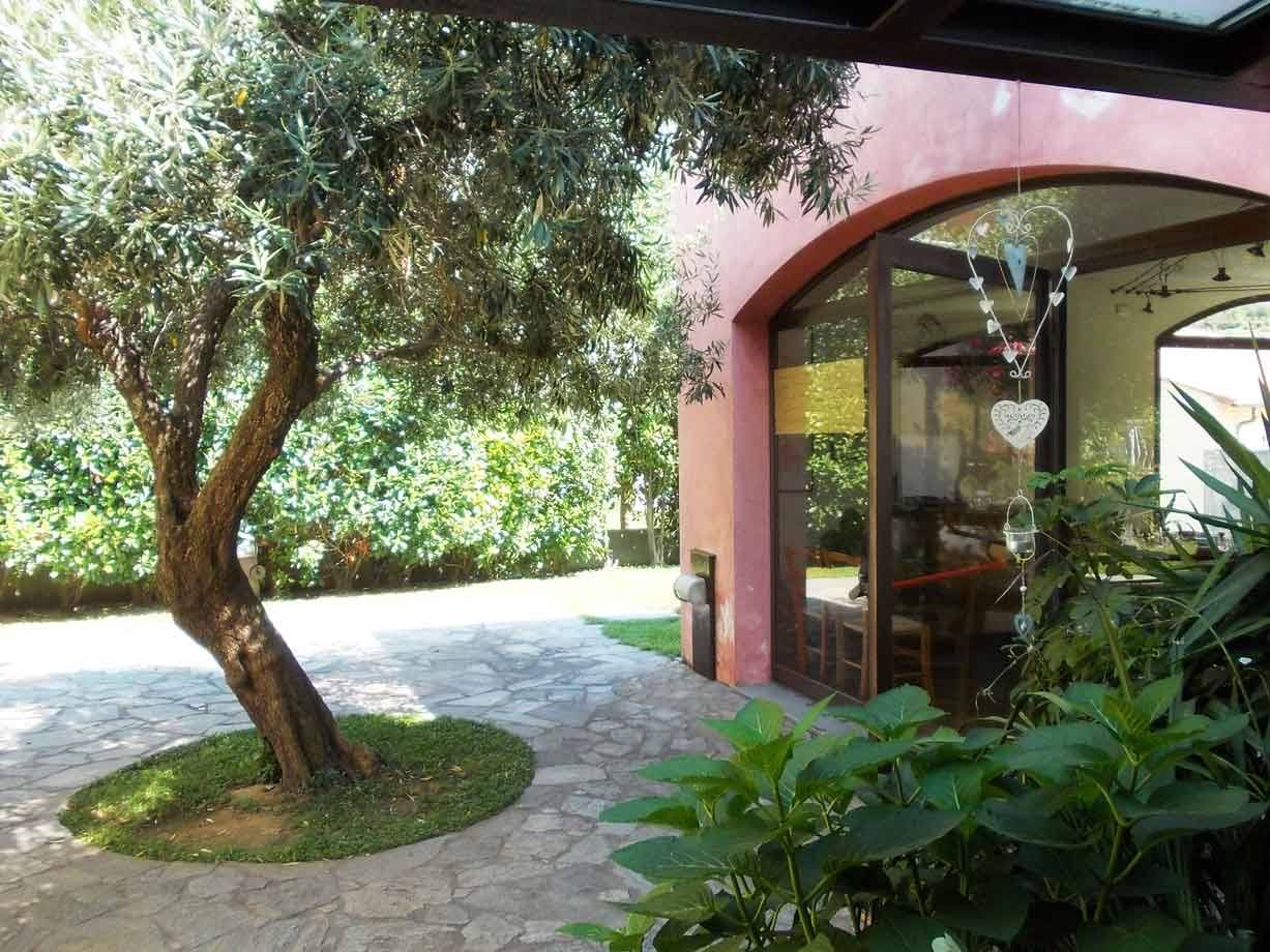 Olio in giardino davanti a una casa rosa con pavimento in pietra