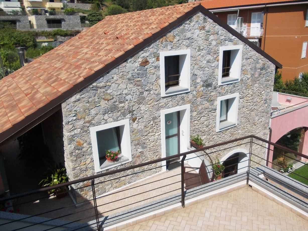 Casa in pietra con tetto di tegole terracotta e terrazza soleggiata
