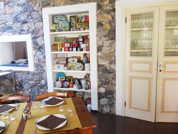 Trattoria dining room with stone wall, vintage tin collection and set table