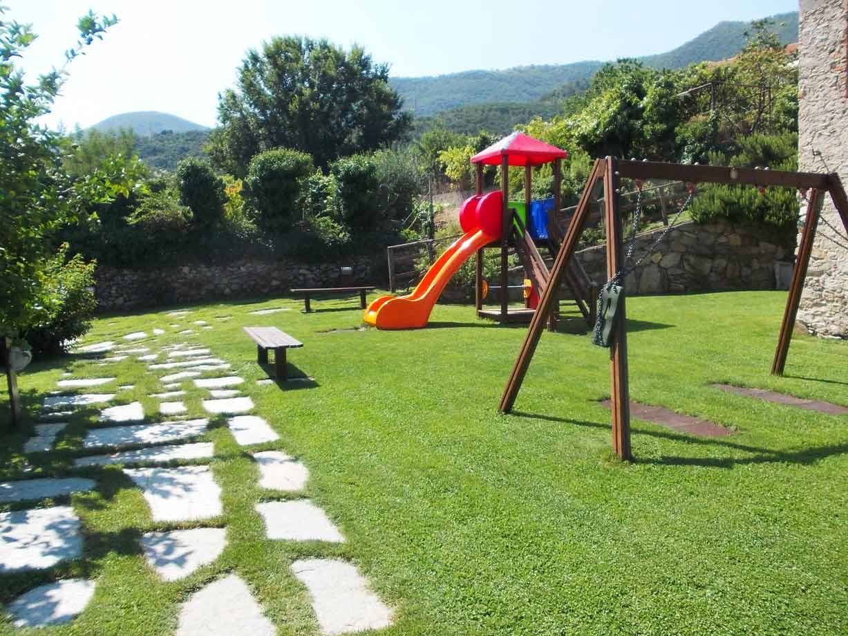 Parco giochi con scivolo arancione e altalena in legno sul prato verde