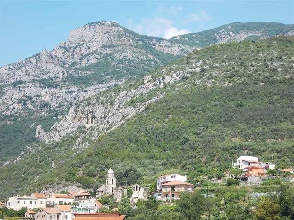village with bell tower among houses and green rocky mountain