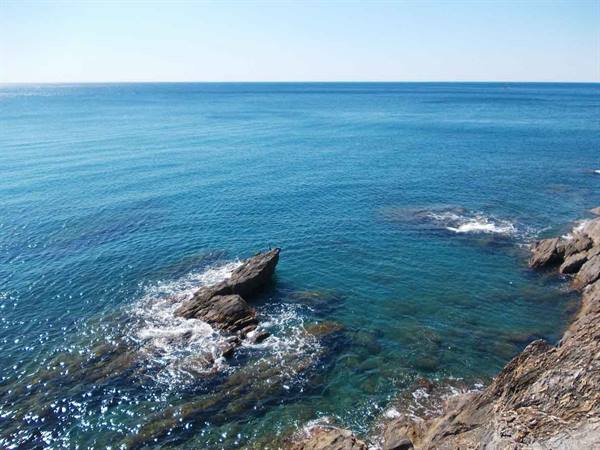 Turquoise water and waves breaking over sunlit rocks by the sea