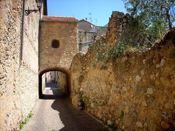 Stone alley with medieval arch and ancient walls under the sun