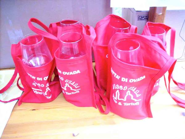 Red tote bags holding wine glasses, Festa di Ovada, wine and truffles