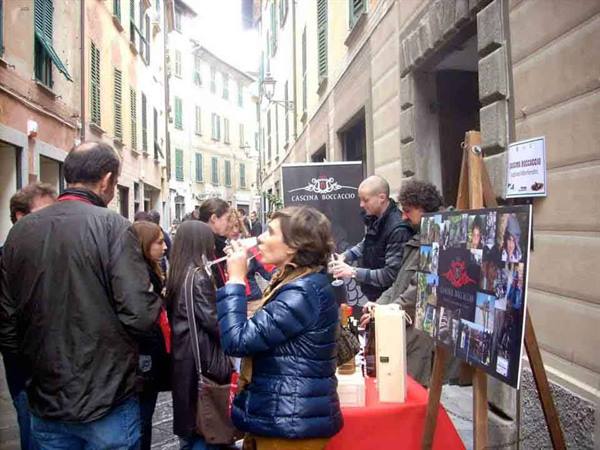 Wine tasting in an alley, woman sips at the Cantina Rocca Grimalda stand