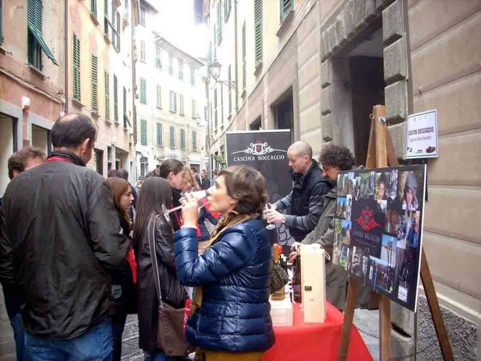 Degustazione di vino in un vicolo, signora assaggia al tavolo della Cantina Rocca Grimalda
