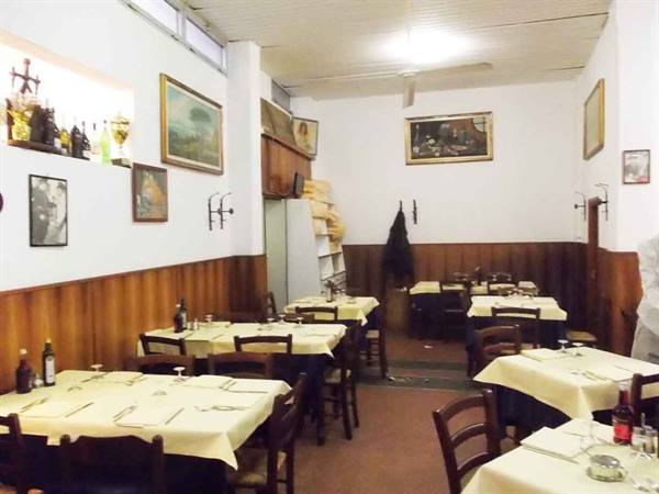 Trattoria dining room with set tables, yellow tablecloths, wooden chairs and paintings on walls