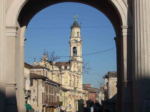 Bell tower and colorful houses seen through a stone arch, blue sky