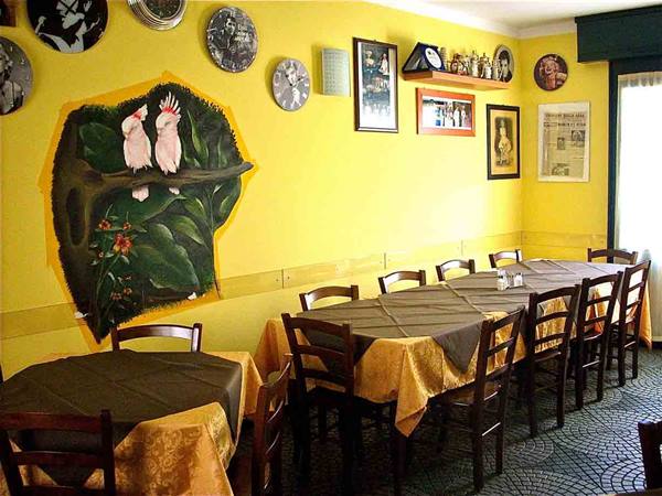 Yellow dining room with set tables, wooden chairs and a cockatoo mural