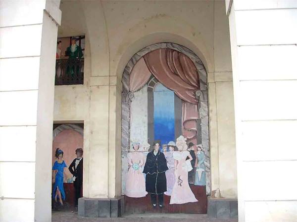 Mural on painted arch: period-costumed figures under pink drapery and blue sky