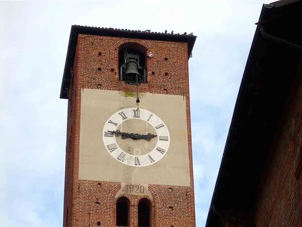 Brick bell tower with Roman numeral clock and bell, year 1920, cloudy sky