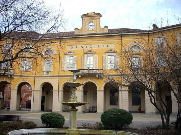 Yellow hospital building with arched loggia, fountain in the foreground