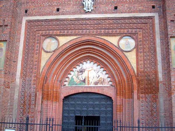 Terracotta church portal with decorated arches and faded frescoes
