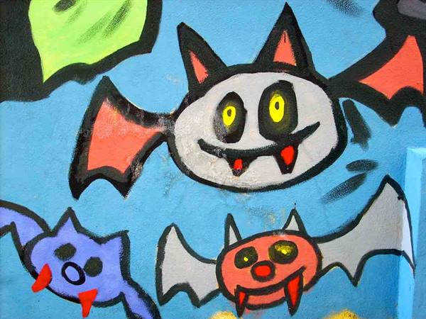 Graffiti mural of colorful cartoon bats painted on blue wall